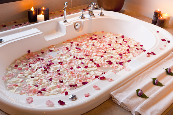 Tub with flower petals and candles